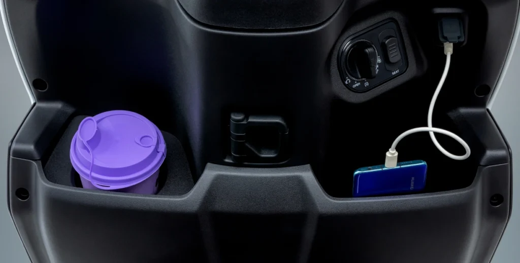 Detalhes do porta-objetos frontal, gancho de sacola e carregador USB da nova Burgman ADX 125.