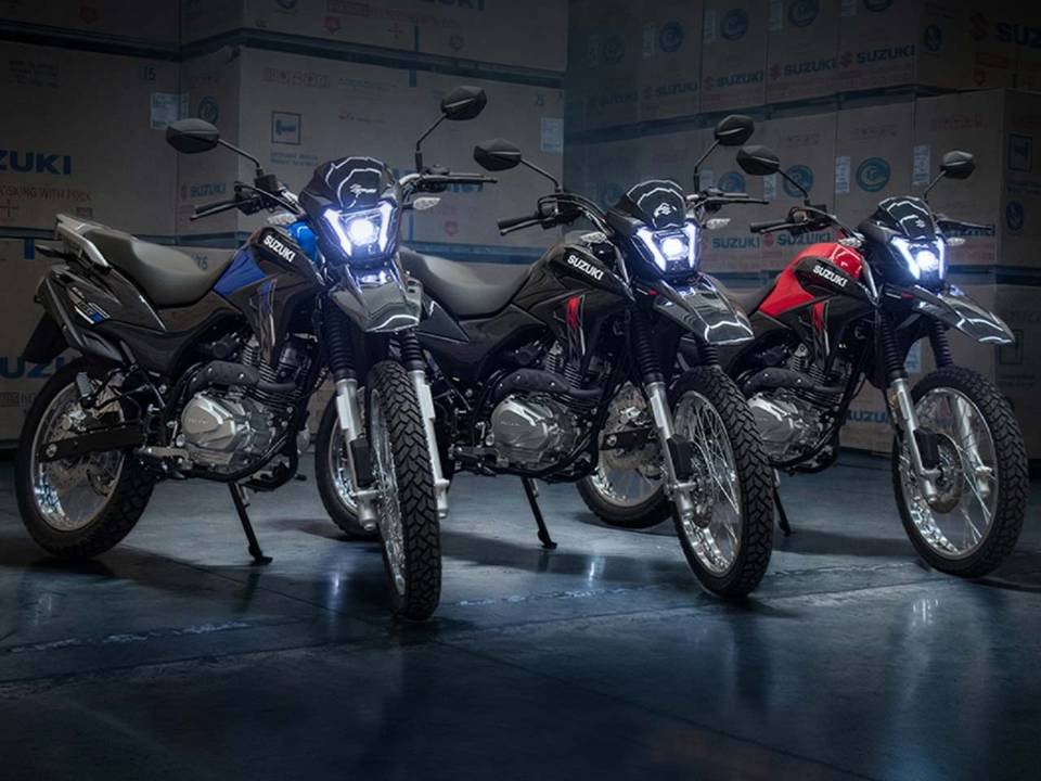 Três motocicletas trail Haojue NK 160 alinhadas nas cores azul, preta e vermelha com faróis acesos.